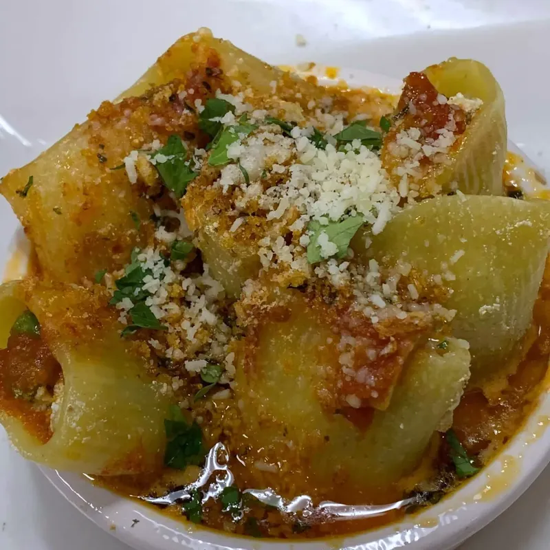 Large stuffed pasta shells in tomato sauce with breadcrumbs and cheese