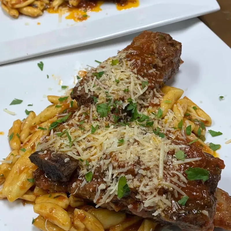 Braised meat over cavatelli in red sauce under grated cheese