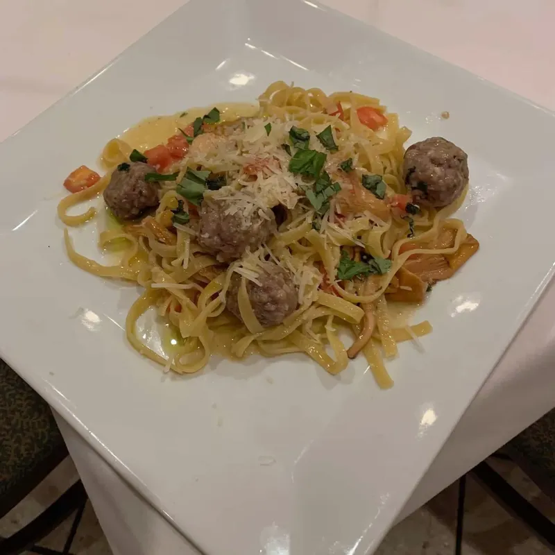 Linguine with meatballs on a square white plate